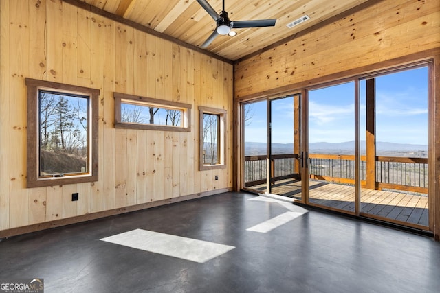 spare room featuring a mountain view, wood ceiling, wooden walls, and a healthy amount of sunlight