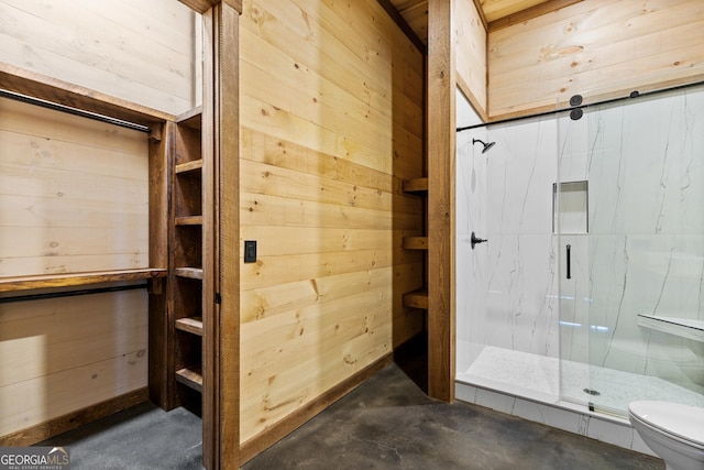 bathroom with toilet, a shower with shower door, and wood walls