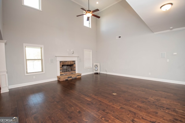 unfurnished living room featuring dark hardwood / wood-style flooring, ornamental molding, ceiling fan, high vaulted ceiling, and a stone fireplace