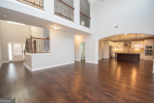 unfurnished living room with dark hardwood / wood-style flooring, sink, and a high ceiling