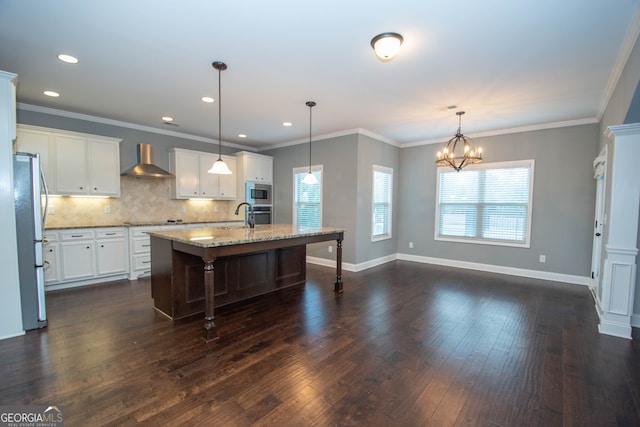 kitchen with a center island with sink, wall chimney range hood, hanging light fixtures, dark hardwood / wood-style floors, and white cabinetry