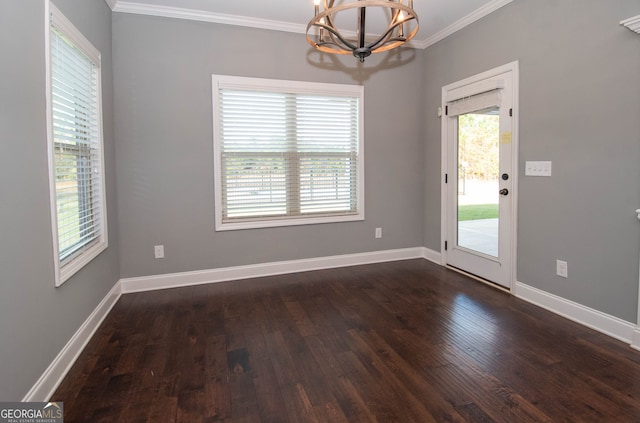 empty room with dark wood-type flooring, crown molding, and a notable chandelier