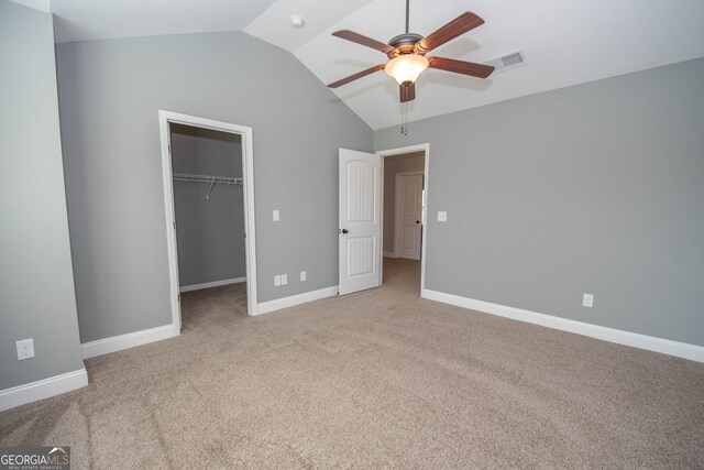 unfurnished bedroom with light colored carpet, ceiling fan, a spacious closet, a closet, and lofted ceiling