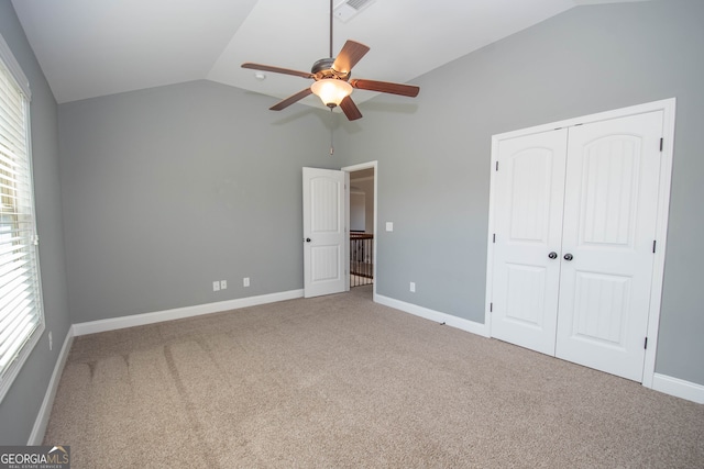 unfurnished bedroom with carpet, ceiling fan, lofted ceiling, and a closet