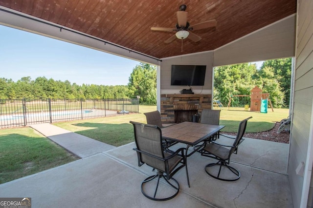 view of patio featuring a playground, ceiling fan, and an outdoor stone fireplace