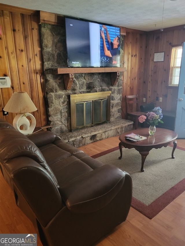 living room with wood-type flooring, wooden walls, and a fireplace