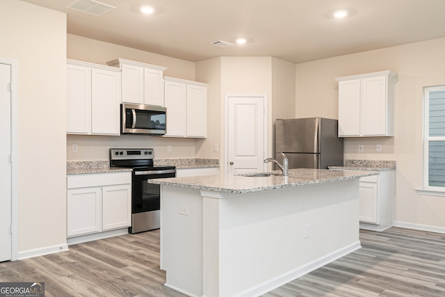 kitchen with appliances with stainless steel finishes, sink, an island with sink, light wood-type flooring, and white cabinets