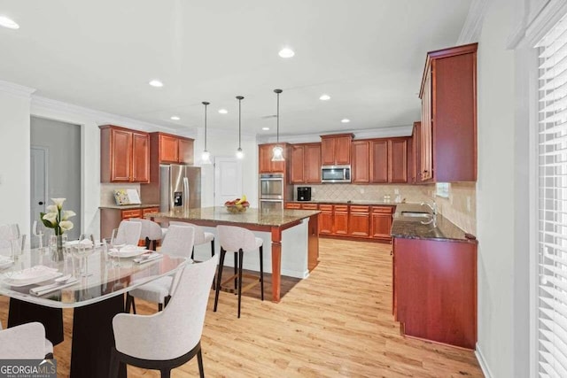 kitchen with a kitchen island, appliances with stainless steel finishes, light hardwood / wood-style floors, a breakfast bar, and decorative backsplash