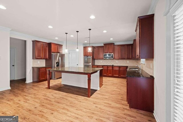 kitchen featuring light wood-type flooring, stainless steel appliances, tasteful backsplash, a kitchen bar, and a kitchen island