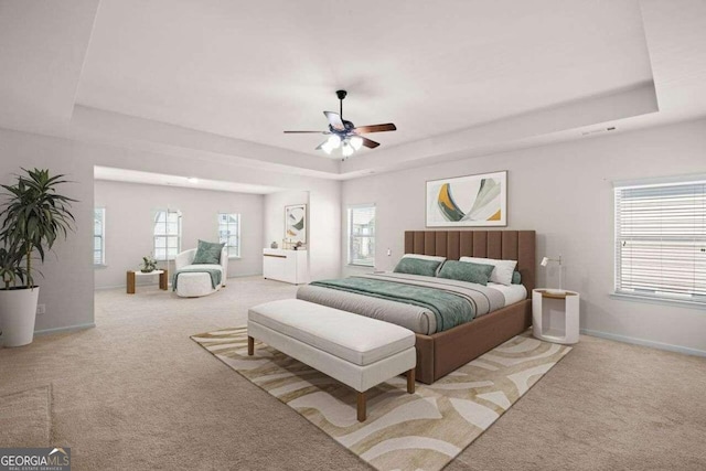 carpeted bedroom featuring multiple windows, a tray ceiling, and ceiling fan