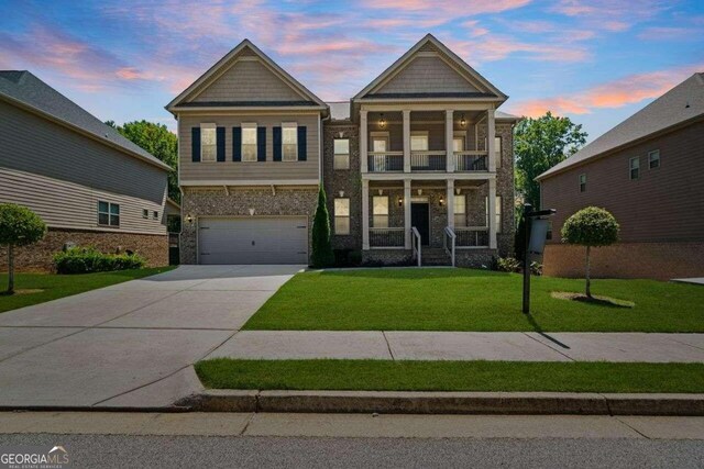 craftsman-style house featuring a balcony, a yard, and a garage