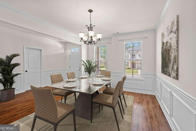 dining room featuring ornamental molding, wood-type flooring, and an inviting chandelier