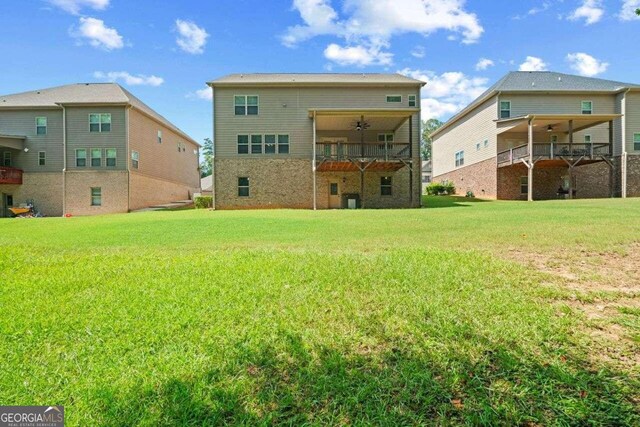 back of house featuring a balcony, a yard, and ceiling fan