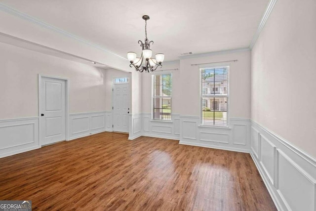 unfurnished dining area with an inviting chandelier, crown molding, and light hardwood / wood-style flooring