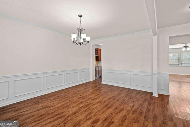 unfurnished dining area with crown molding, ceiling fan with notable chandelier, and hardwood / wood-style floors