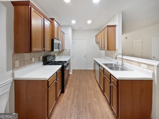 kitchen with appliances with stainless steel finishes, sink, light hardwood / wood-style flooring, kitchen peninsula, and decorative backsplash