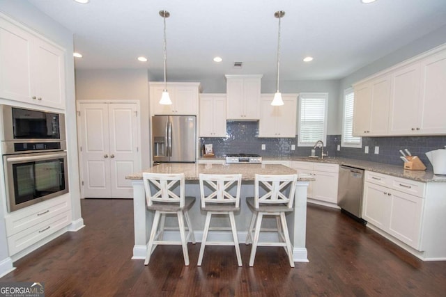 kitchen featuring a center island, stainless steel appliances, dark hardwood / wood-style flooring, and white cabinets