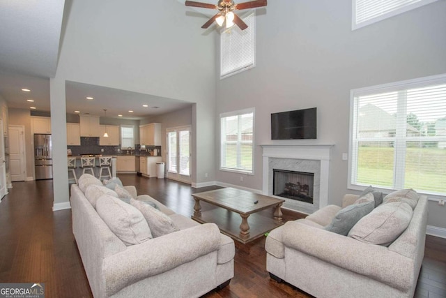 living room featuring ceiling fan, dark hardwood / wood-style floors, and a high ceiling