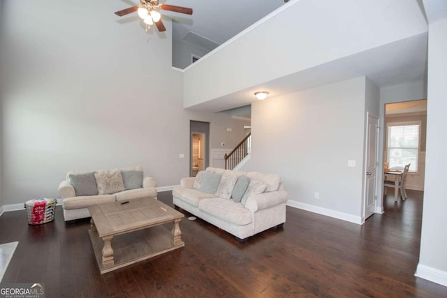 living room featuring ceiling fan, dark hardwood / wood-style floors, and a high ceiling