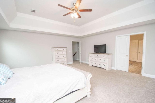 bedroom with a tray ceiling, ceiling fan, and light colored carpet