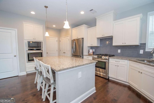 kitchen featuring appliances with stainless steel finishes, a kitchen island, and dark hardwood / wood-style flooring