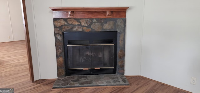 details featuring a stone fireplace and wood finished floors