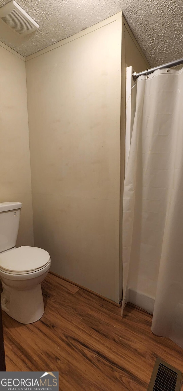 full bathroom with visible vents, a textured ceiling, toilet, and wood finished floors