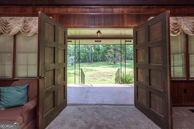 doorway with wood walls and carpet flooring