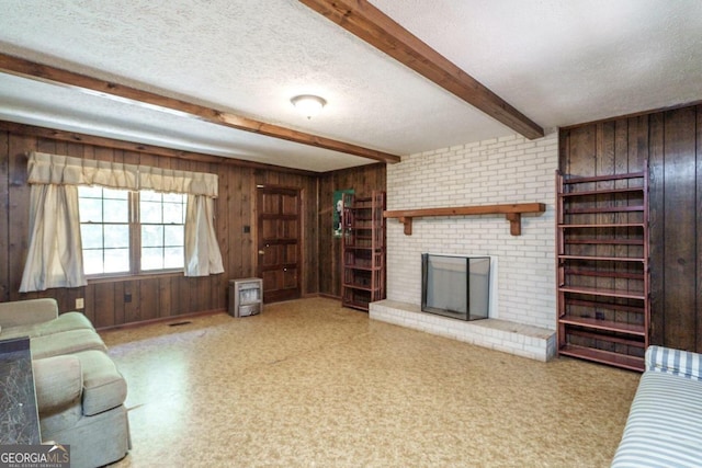 living room with brick wall, wooden walls, a brick fireplace, beam ceiling, and a textured ceiling