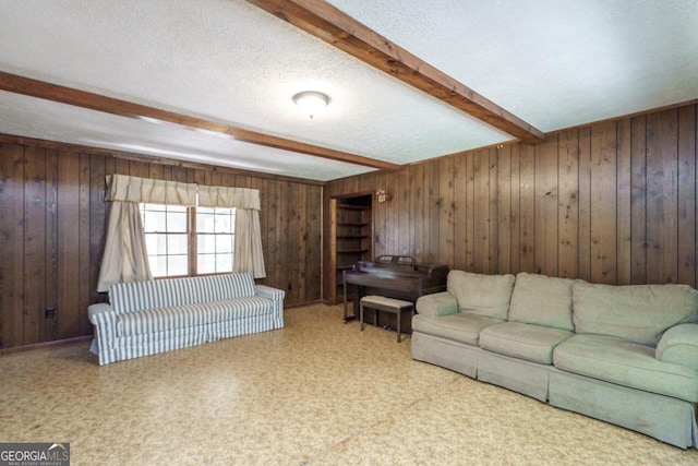 carpeted living room with a textured ceiling, wooden walls, and beamed ceiling