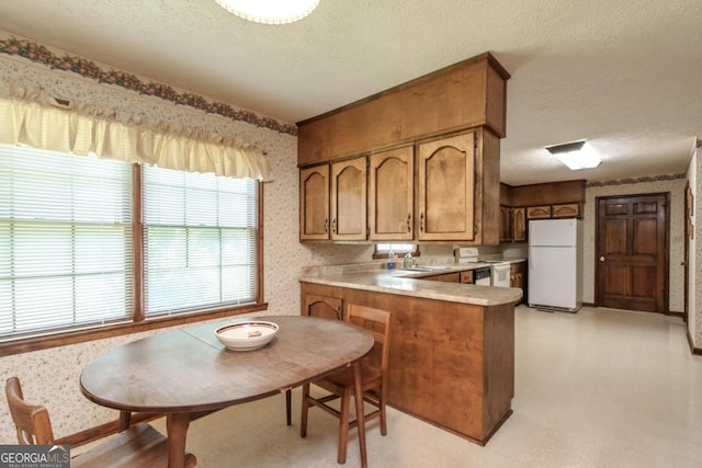 kitchen with sink, kitchen peninsula, a textured ceiling, and white appliances