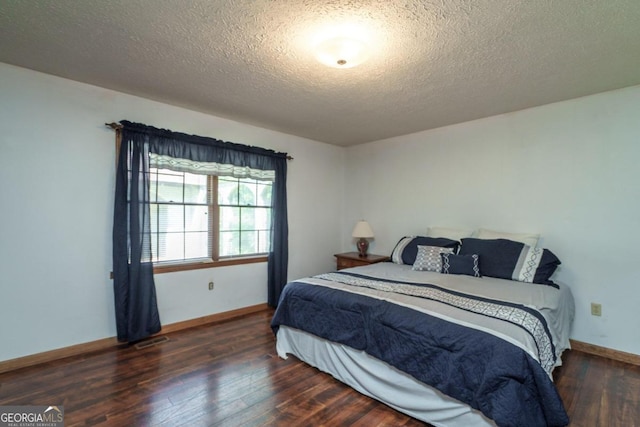 bedroom with a textured ceiling and dark hardwood / wood-style floors