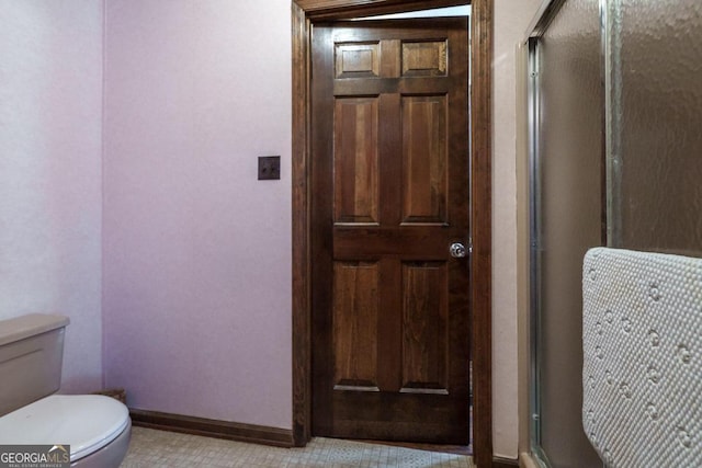 bathroom featuring tile patterned flooring, a shower with shower door, and toilet