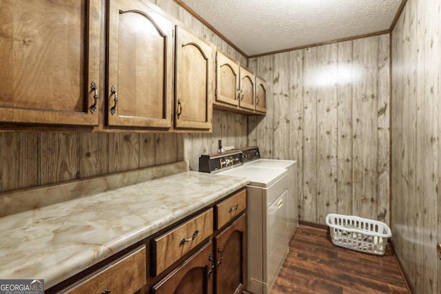 laundry area with dark hardwood / wood-style floors, washing machine and dryer, cabinets, a textured ceiling, and wooden walls