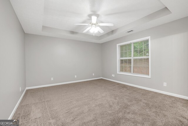 spare room featuring ceiling fan, carpet flooring, and a raised ceiling