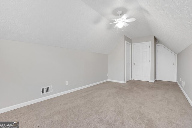 bonus room featuring a textured ceiling, ceiling fan, vaulted ceiling, and light colored carpet