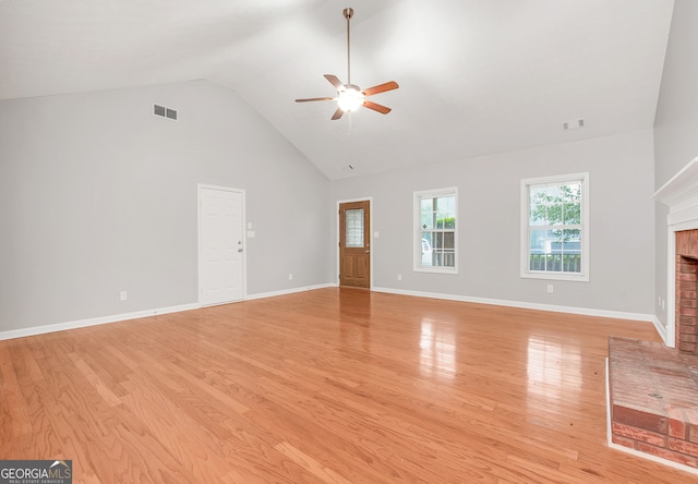 unfurnished living room featuring high vaulted ceiling, ceiling fan, light wood-type flooring, and a brick fireplace