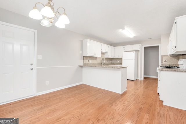 kitchen with light hardwood / wood-style flooring, white cabinetry, tasteful backsplash, kitchen peninsula, and white refrigerator