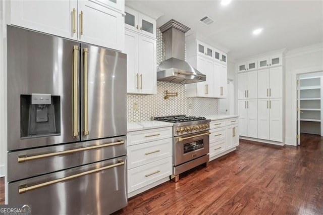 kitchen featuring backsplash, stainless steel appliances, wall chimney exhaust hood, light stone countertops, and dark hardwood / wood-style flooring