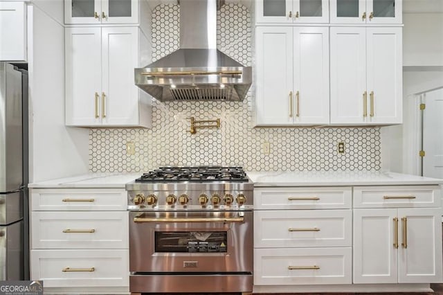 kitchen featuring white cabinetry, stainless steel appliances, wall chimney exhaust hood, and decorative backsplash