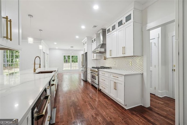 kitchen with stainless steel appliances, decorative backsplash, white cabinetry, wall chimney exhaust hood, and dark hardwood / wood-style flooring