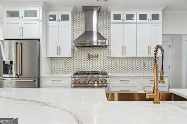 kitchen featuring backsplash, high quality appliances, and wall chimney exhaust hood