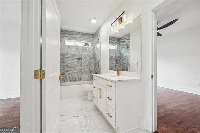 full bathroom with ceiling fan, toilet, vanity, hardwood / wood-style flooring, and tiled shower / bath combo