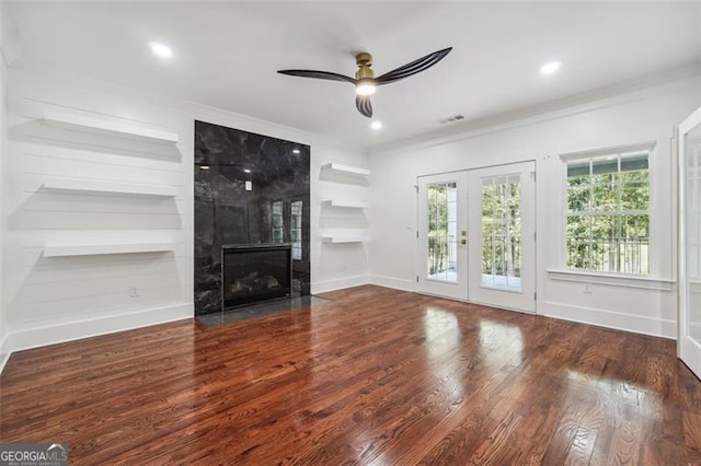 unfurnished living room with built in shelves, french doors, dark hardwood / wood-style floors, ceiling fan, and a premium fireplace