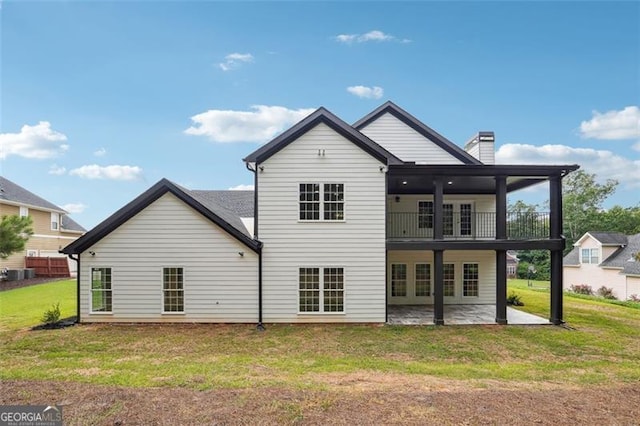 rear view of property featuring a patio, a yard, and a balcony