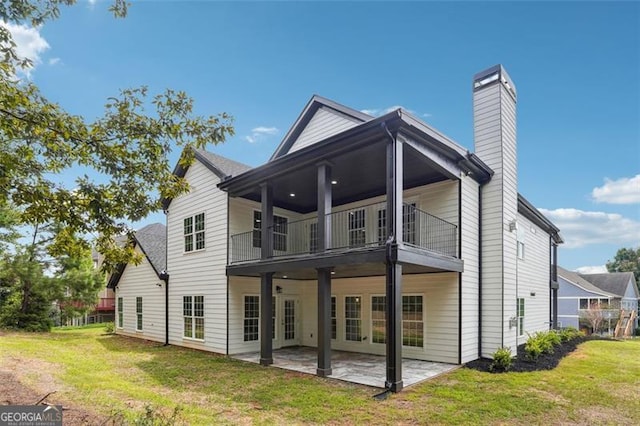 rear view of property with a patio, a yard, and a balcony