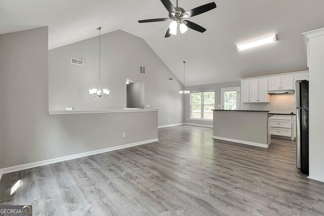 kitchen with backsplash, wood-type flooring, ceiling fan with notable chandelier, stainless steel refrigerator, and white cabinets