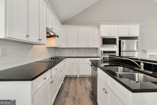 kitchen featuring sink, lofted ceiling, hardwood / wood-style flooring, stainless steel appliances, and white cabinets