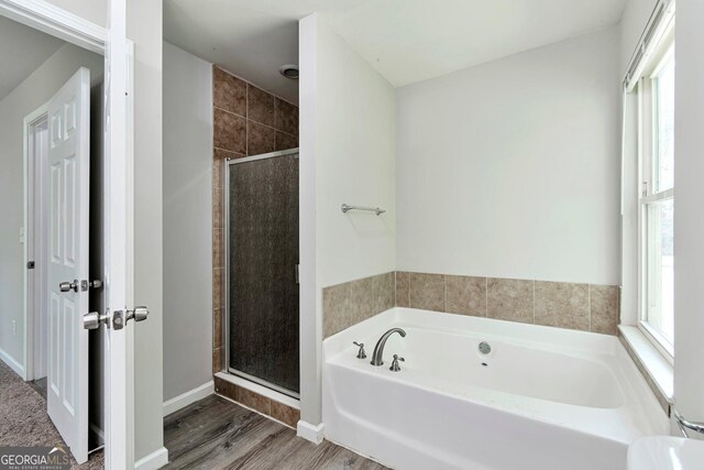 bathroom with hardwood / wood-style flooring and separate shower and tub