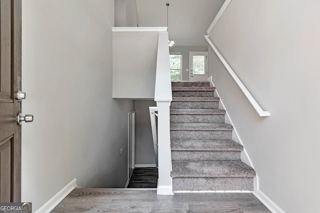 stairway with vaulted ceiling and hardwood / wood-style flooring